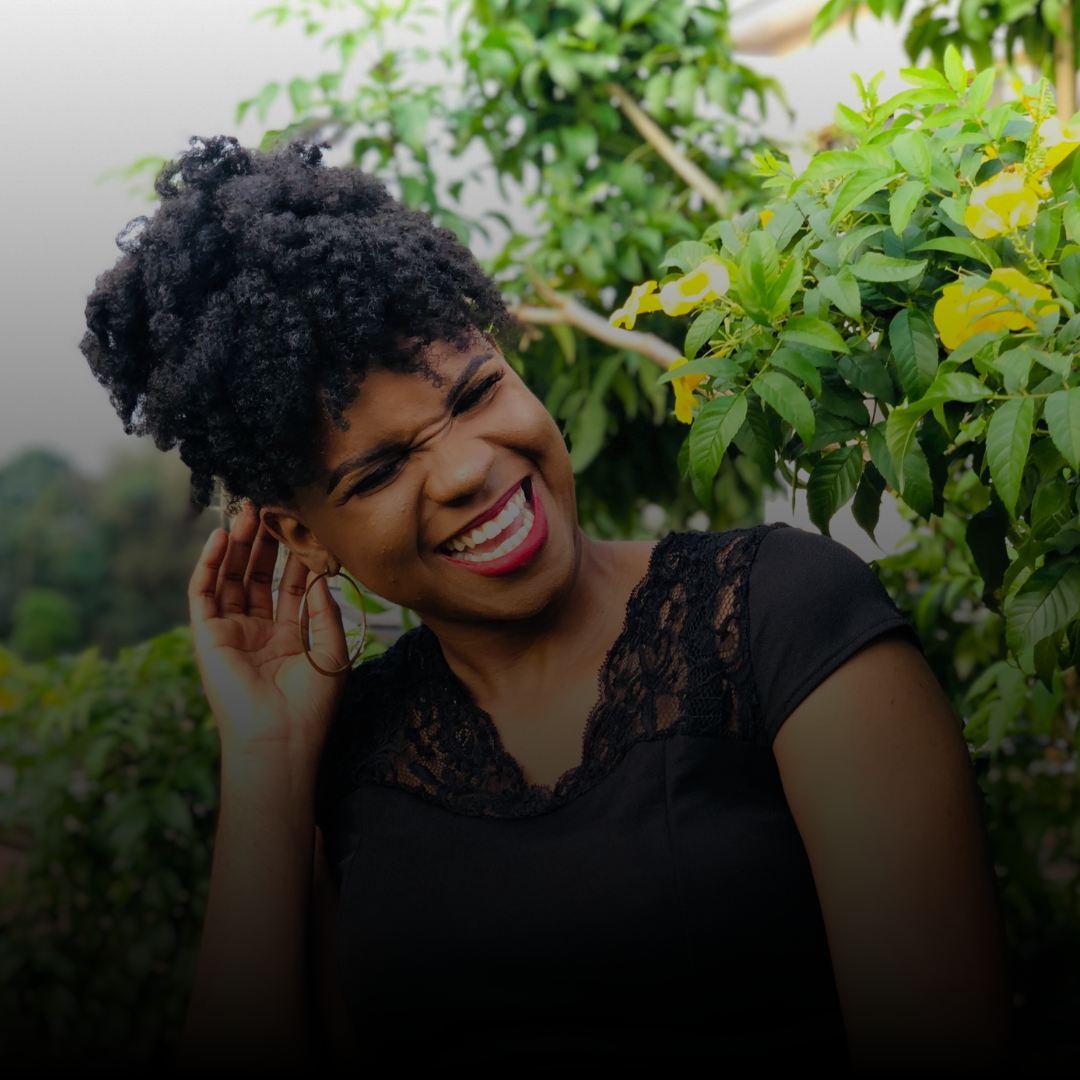 joyful, empowered black woman smiling in front of yellow flowers
